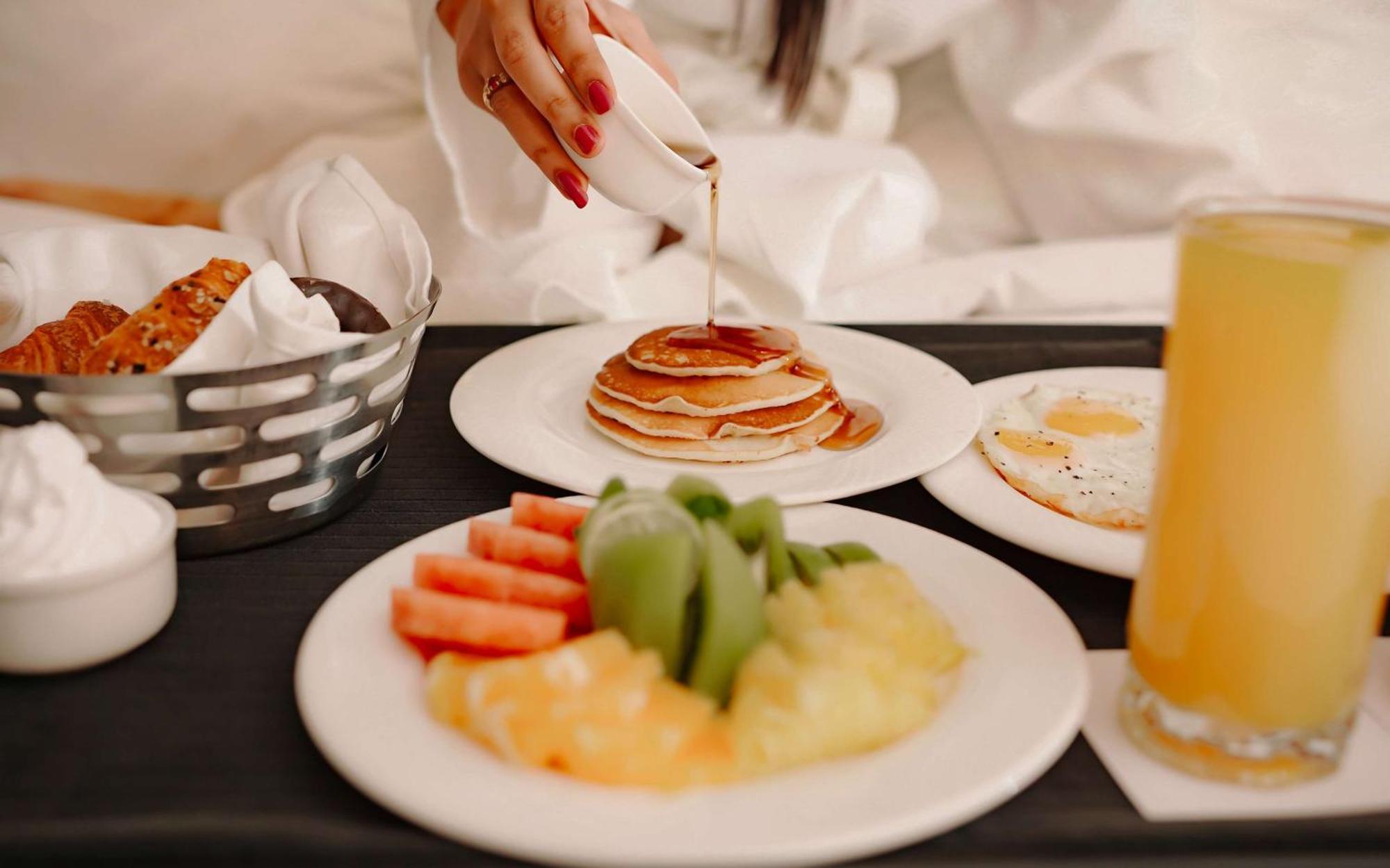 Radisson Blu Hotel Amritsar Esterno foto A woman pouring maple syrup on a stack of pancakes